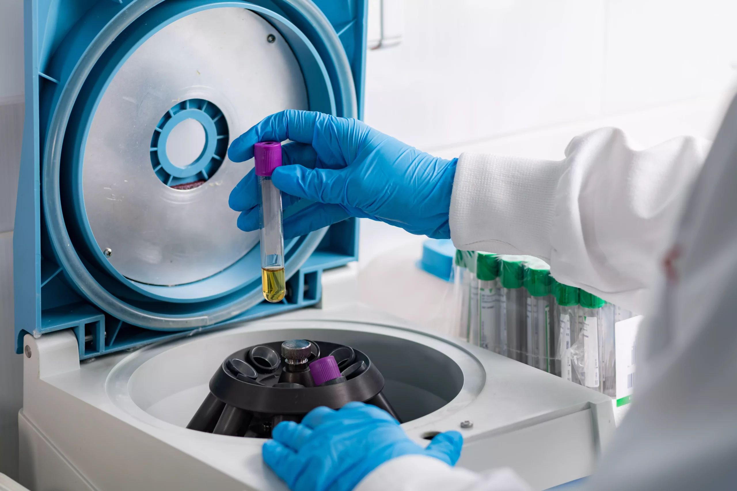 Scientist in lab operating centrifuge with blue gloves on hands